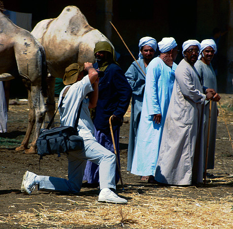 Photographer snaps pictures at camel market.