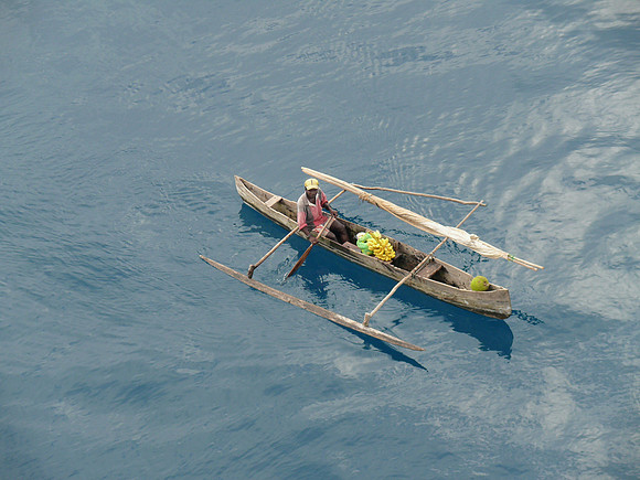 Man selling fruit from outrigger canoe.
