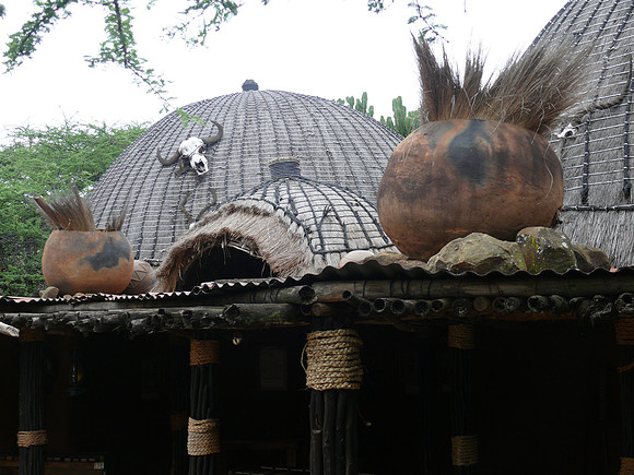 Thatched roof decorated with skull and pots.