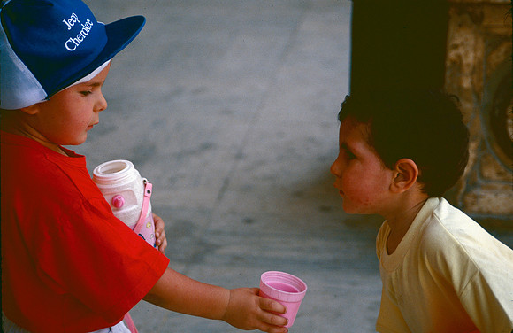 A boy offers a drink to his friend.