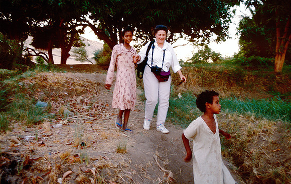 A young girl and her brother lead a tourist along a path